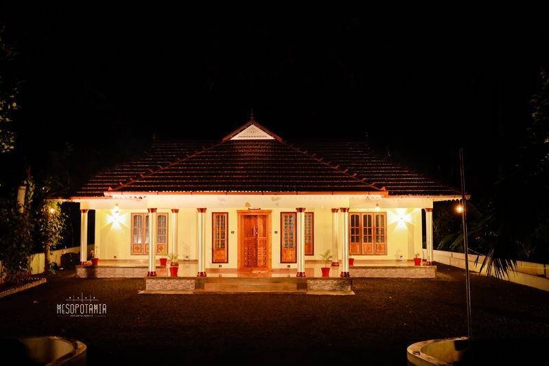 A pitched, tiled roof over a courtyard plan — carved timber, turned columns and jaali screens doing the work.